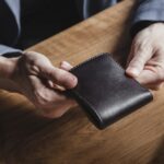 A,Business,Man,At,A,Wooden,Table,Holds,A,Leather