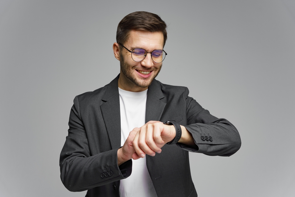 Man,In,Black,Suit,Checks,Smartwatch,With,A,Smile,During